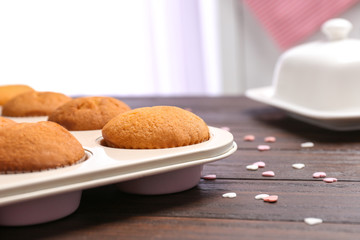 Baking tray with tasty cupcakes on table. Fresh from oven
