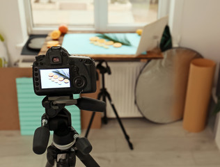 Professional camera with picture of cut fruits and palm leaf on display in studio. Food photography