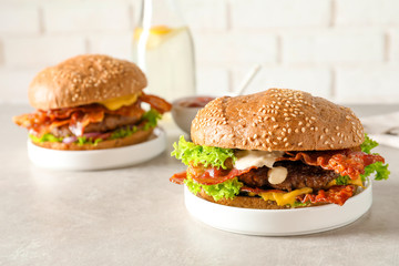 Tasty burgers with bacon on table