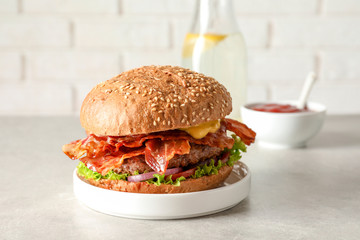 Tasty burger with bacon on table