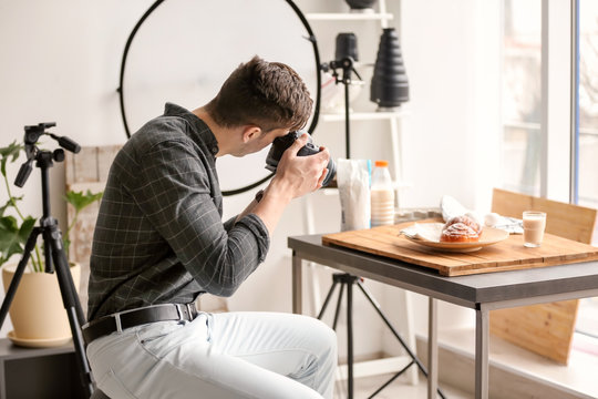 Young man taking picture of food in photo studio
