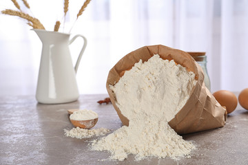 Paper bag and spoon with flour on table