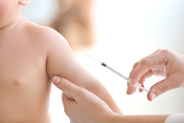 Doctor vaccinating baby in clinic, closeup