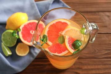Tasty lemonade with citrus fruits in pitcher on table