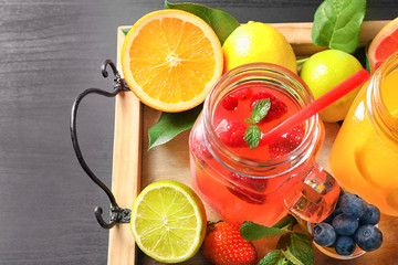 Tasty lemonades with berries and citrus fruits in mason jars on table