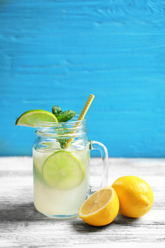 Tasty lemonade with lime and mint in mason jar on table