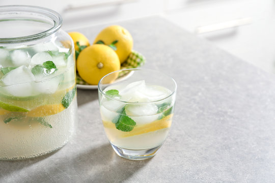 Jar and glass of fresh lemonade on table