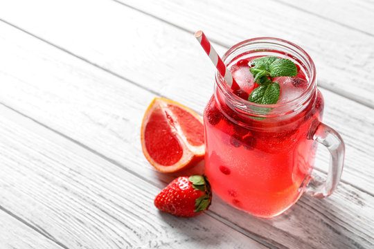 Mason jar of fresh lemonade with berries on table