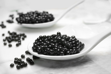 Spoons with delicious black caviar on marble board