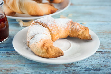 Plate with tasty crescent roll on table