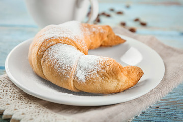 Plate with tasty crescent roll on table