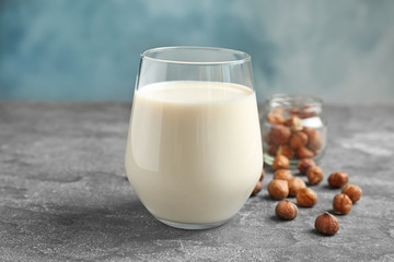Glass with hazelnut milk on grey table