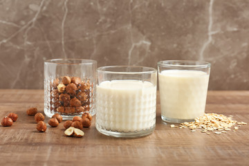 Glasses with hazelnut and oat milk on wooden table
