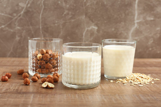 Glasses with hazelnut and oat milk on wooden table