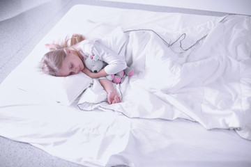 Obraz na płótnie Canvas Child little girl sleeps in the bed with a toy teddy bear