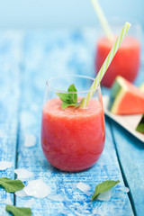Fresh watermelon smoothie in two glasses on a blue wooden rustic background