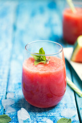 Fresh watermelon smoothie in two glasses on a blue wooden rustic background. Closeup shot.