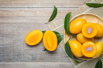 Fresh yellow marian plum fruit (Mayongchid in Thai name) on wooden table. Top view