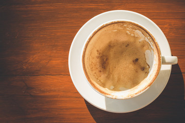Empty white coffee cup with latte foam after drinking on wooden table with copy space for text or design