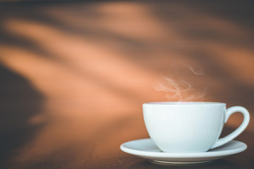 White coffee cup on wooden table or counter in coffee shop and blur light bokeh background