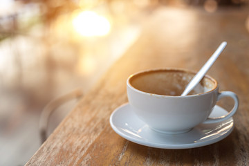 White coffee cup on wooden table or counter in coffee shop and blur light bokeh background