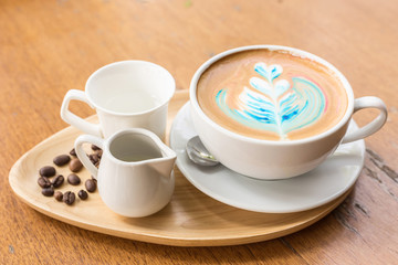 Hot art latte coffee in white cup on wooden table in the coffee shop
