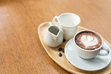 Colorful rainbow latte coffee in white cup on wooden table with copy space for text or design