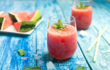 Fresh watermelon smoothie with ice in two glasses on a blue wooden rustic background