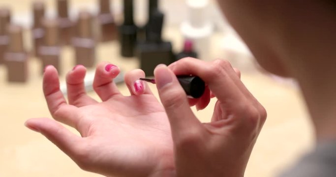 Woman applying color gel on her nail at home
