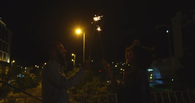 Couple holding sparkles in city 