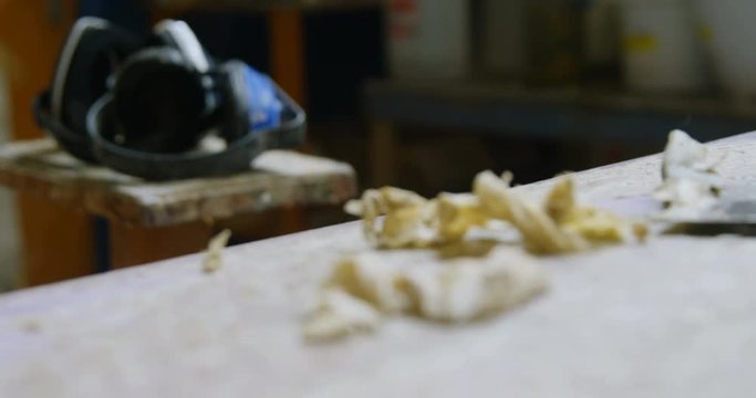 Earmuffs and surfboard shaper in workshop 