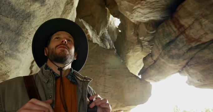 Male hiker standing with backpack in the cave 