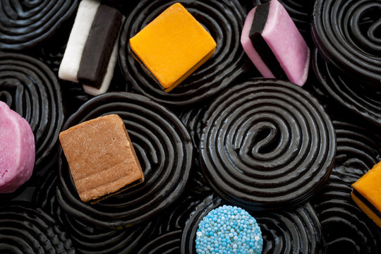 Black liquorice swirls, chewy candy and delicious dessert concept with macro close up on licorice wheels and other assorted licorice with a mix of colors and shapes