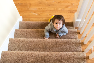Toddler boy climbing a staircase in his house