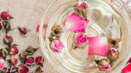 A cup of tea pink rose on a white wooden table.