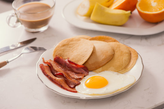 Breakfast plate with pancakes, eggs, bacon and fruit.