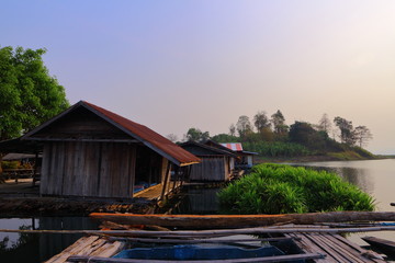 Water Village at the edge of river with mountain behind the scene, natural habitat in Kanchanaburi Province, Thailand.