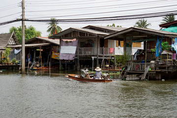 Fototapeta na wymiar In view of the houses along the river in Thailand. The boat ride over to sell to the people who live along the canal.