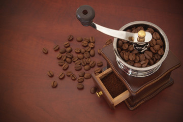 Vintage manual coffee grinder and arabica coffee beans on wooden table