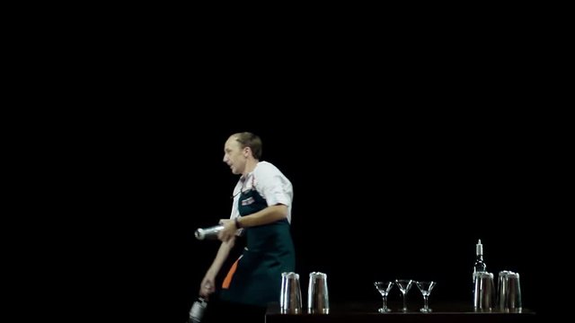 Isolated: Bartender juggling the objects (bottles and shakers) on black background