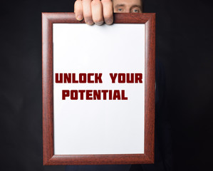 In the hands of a businessman a frame with the inscription:UNLOCK YOUR POTENTIAL