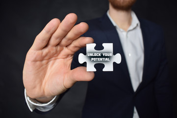 Businessman holding a puzzle with the inscription:UNLOCK YOUR POTENTIAL