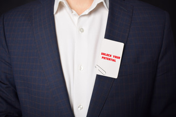 Businessman shows business card with the inscription:UNLOCK YOUR POTENTIAL