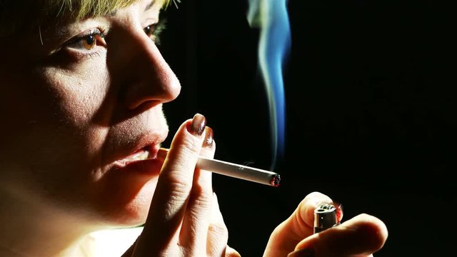 4K.Woman  do fire with lighter and  smoke cigarette . Close up 