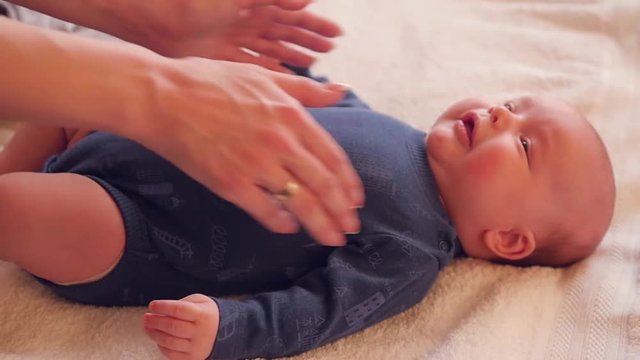 A young mother strokes her cute little two month old son, he likes. HD, 1920x1080. slow motion.