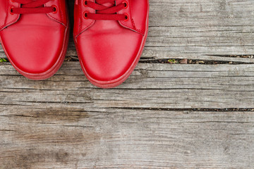 Red sneakers on old wooden cracked background. Top view with copy space. Close up. Stylish background.
