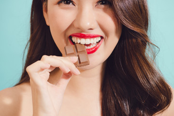 Attractive young asian woman eating chocolate, closeup