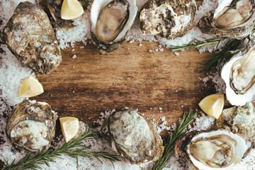 fresh just opened oysters and slice of lemon on rustic wooden background