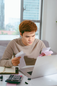 Focused Asian man paying his bills in the living room