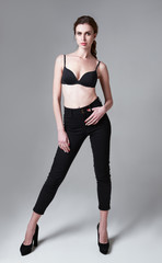 Fototapeta na wymiar Studio fashion shot: portrait of attractive young woman in pants and bra. Full length